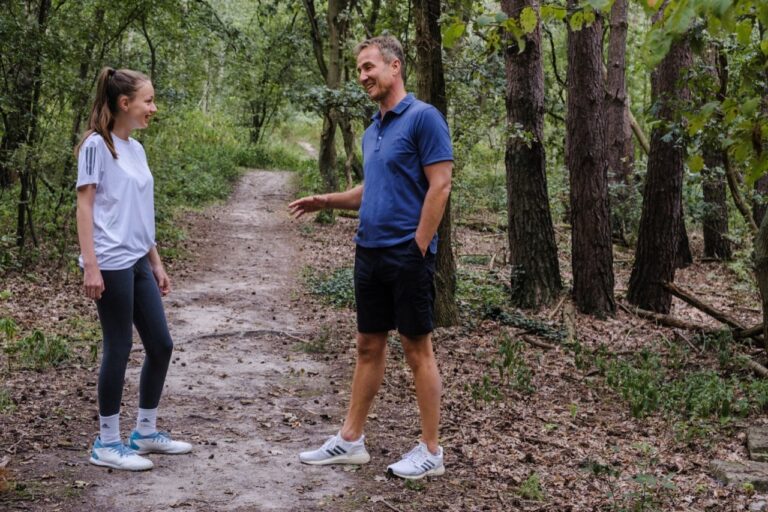junge sportlerin und coach im gespräch auf waldweg – selbstvertrauen im sport aufbauen