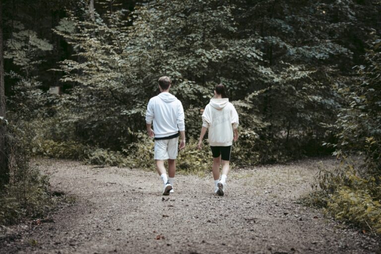 zwei junge sportler:innen gehen einen waldweg entlang, symbolbild für selbstbewusstsein stärkende übungen